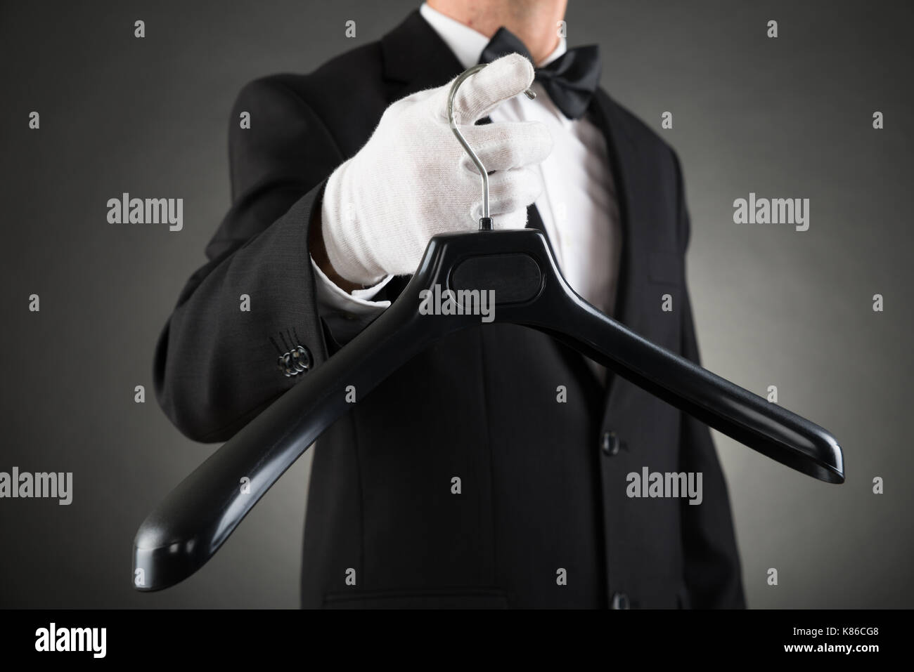 Close-up Of Housekeeper In Suit Holding Black Plastic Hanger Stock Photo