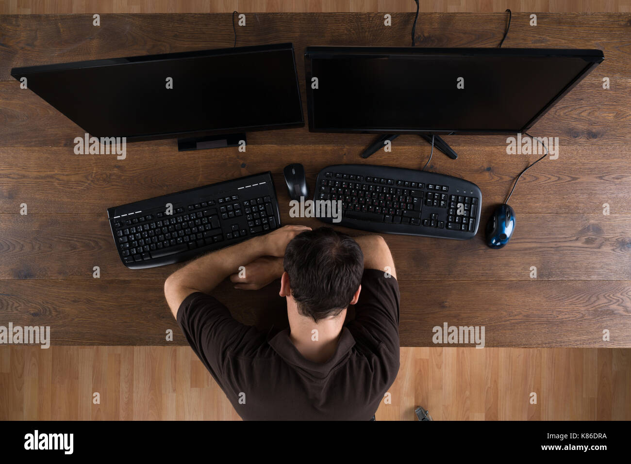 Man Sleeping At Desk With Computers Showing Program Code Stock Photo