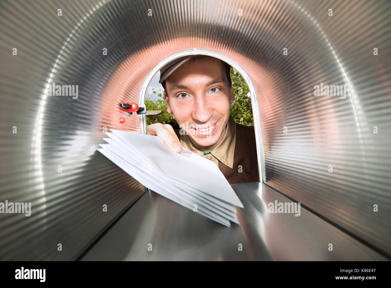 Close-up Of Happy Mailman Placing Envelopes View From Inside The Mailbox Stock Photo
