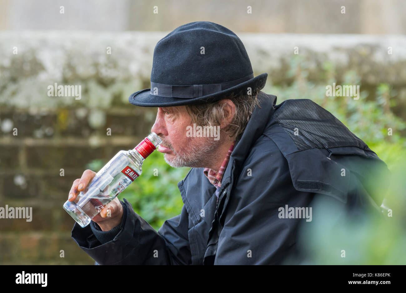 Man outside drinking in the daytime, appearing to be homeless, in the South of England, UK. Man drowning his sorrows. Stock Photo