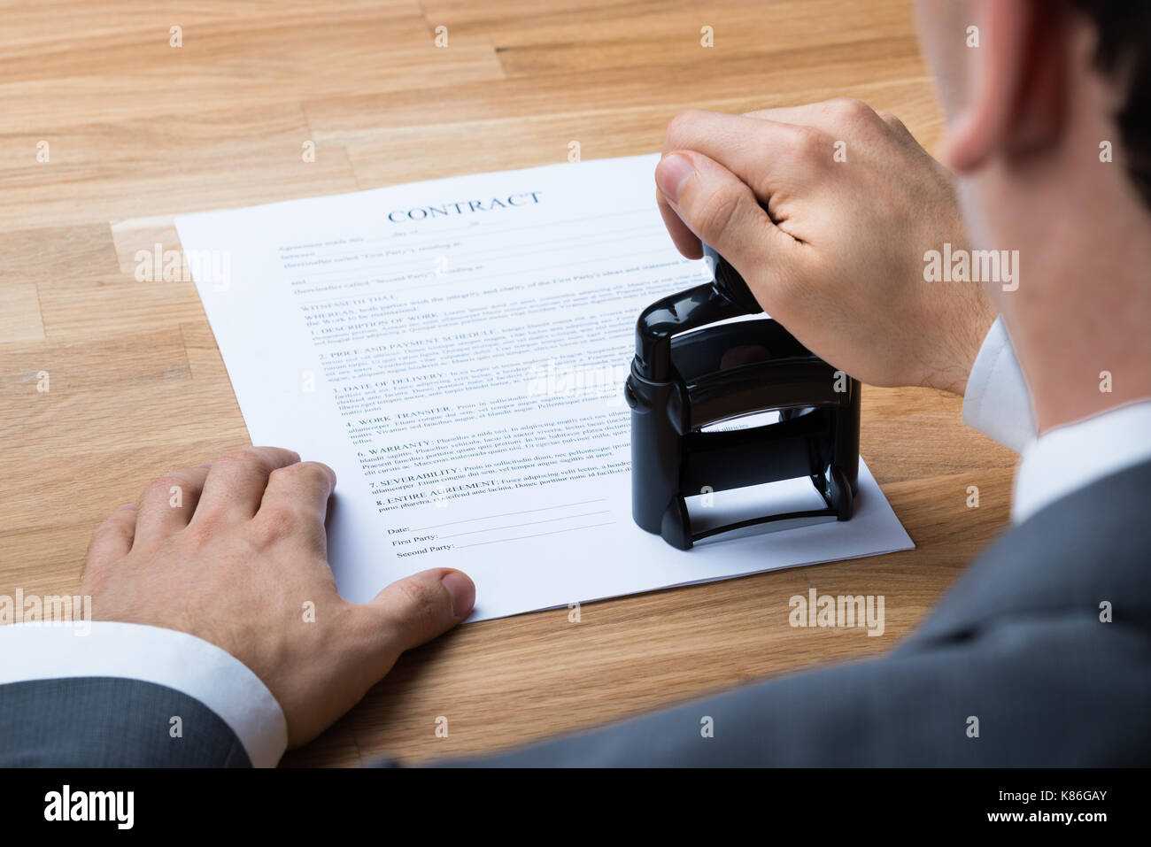 Cropped image of businessman stamping contract document at office desk Stock Photo