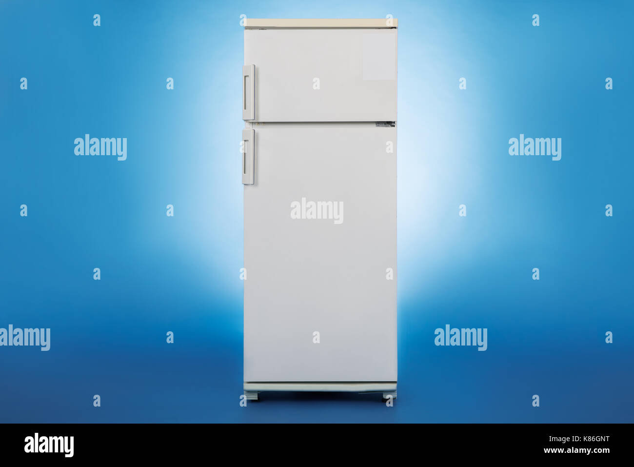 Photo of closed refrigerator isolated over blue background Stock Photo