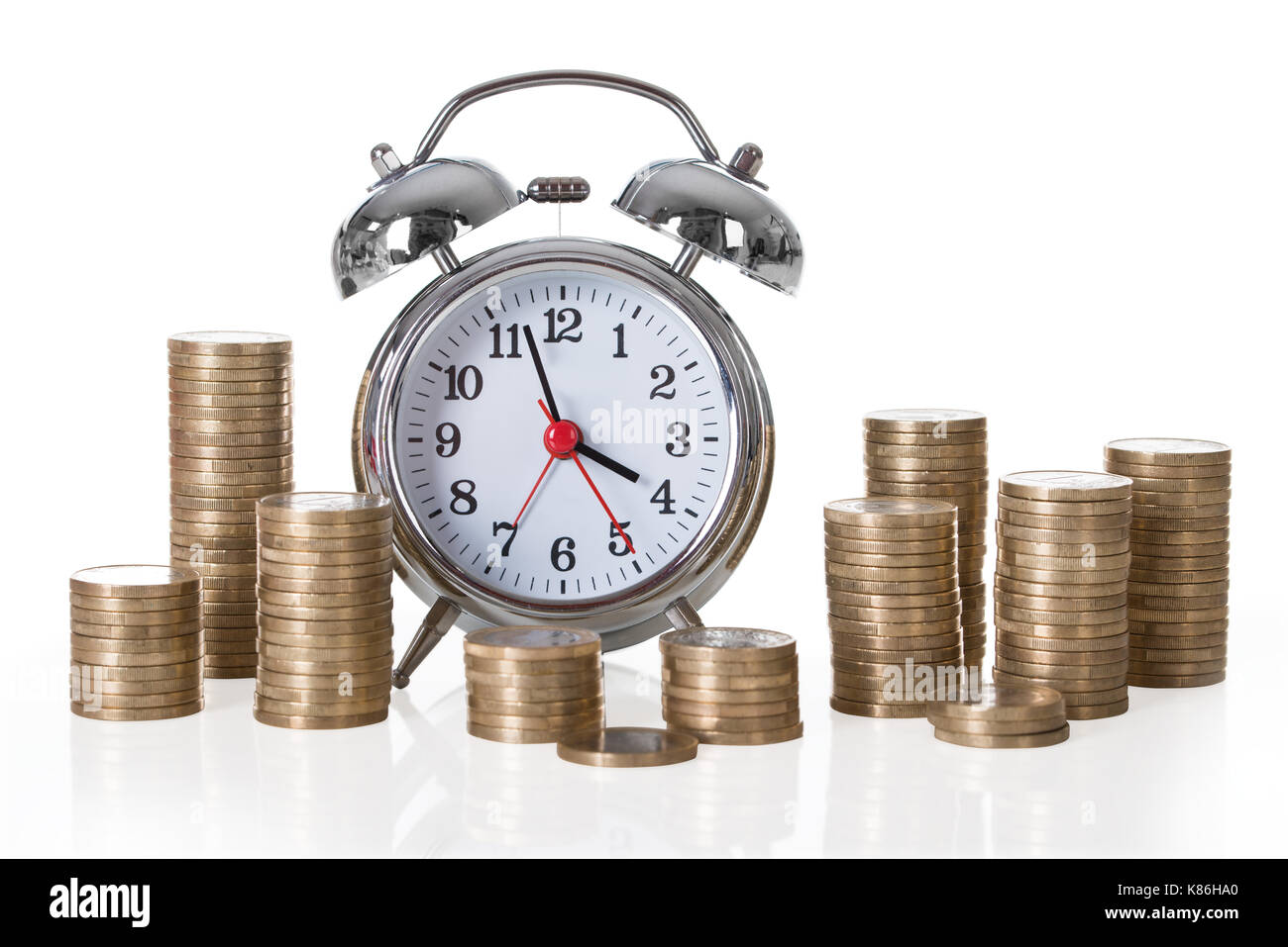 Alarm clock and coin stacks isolated over white background Stock Photo