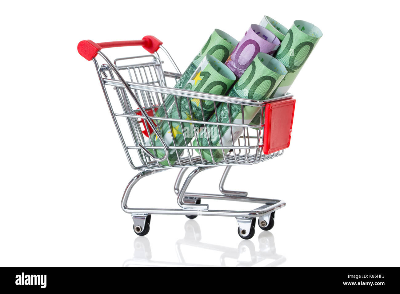 Rolled euro notes in shopping cart on table against white background Stock Photo