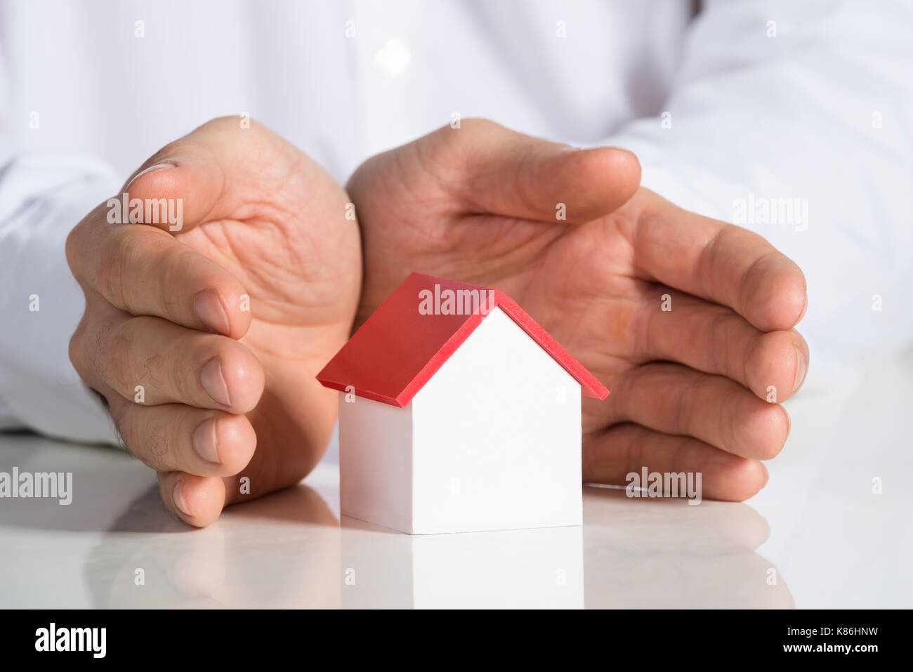 Midsection of businessman protecting house model at office desk Stock Photo