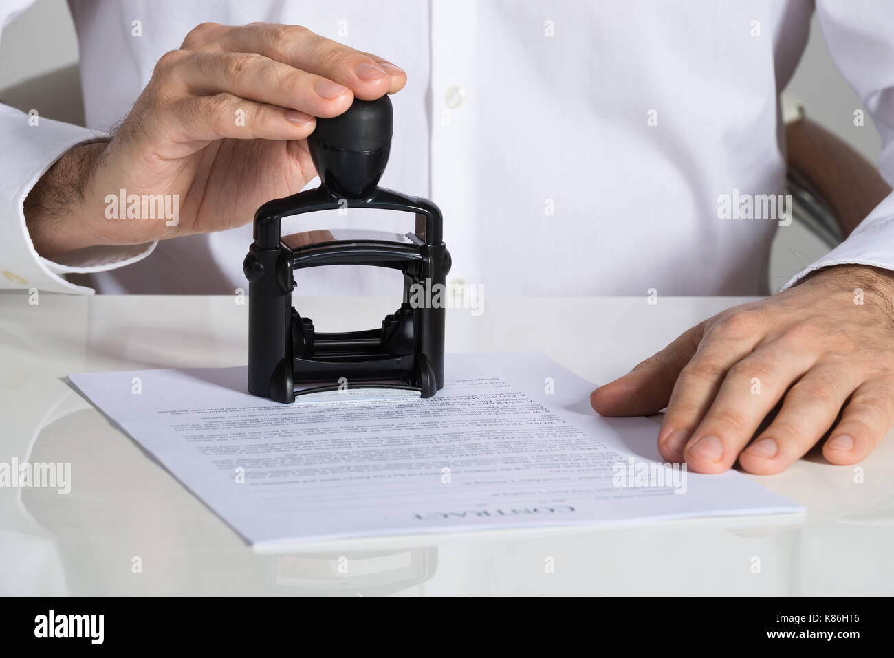 Midsection of businessman stamping contract document at office desk Stock Photo