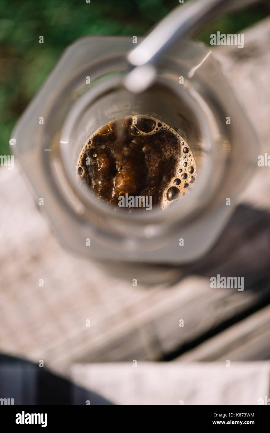 Fresh morning aeropressed coffee being brewed outdoor on the old wooden table background Stock Photo
