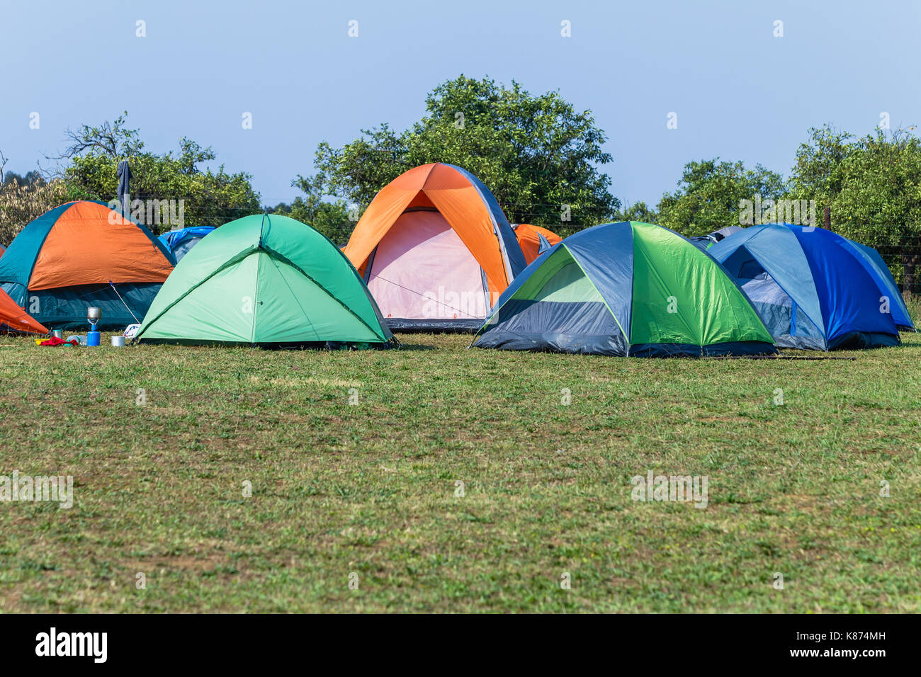 Camping tents a dozen spread over grass field rural mountain