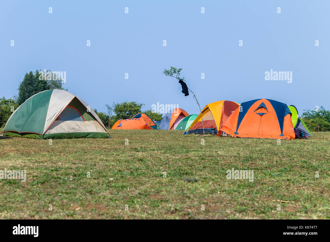 Camping tents a dozen spread over grass field rural mountain