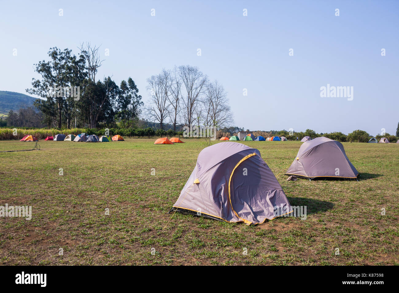 Camping tents a dozen spread over grass field rural mountain