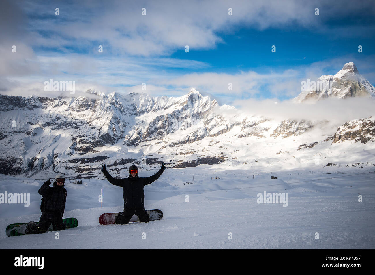 Two snowboarders cheering overlooking the iconic Matterhorn peak, taken in Zermatt, Switzerland Stock Photo