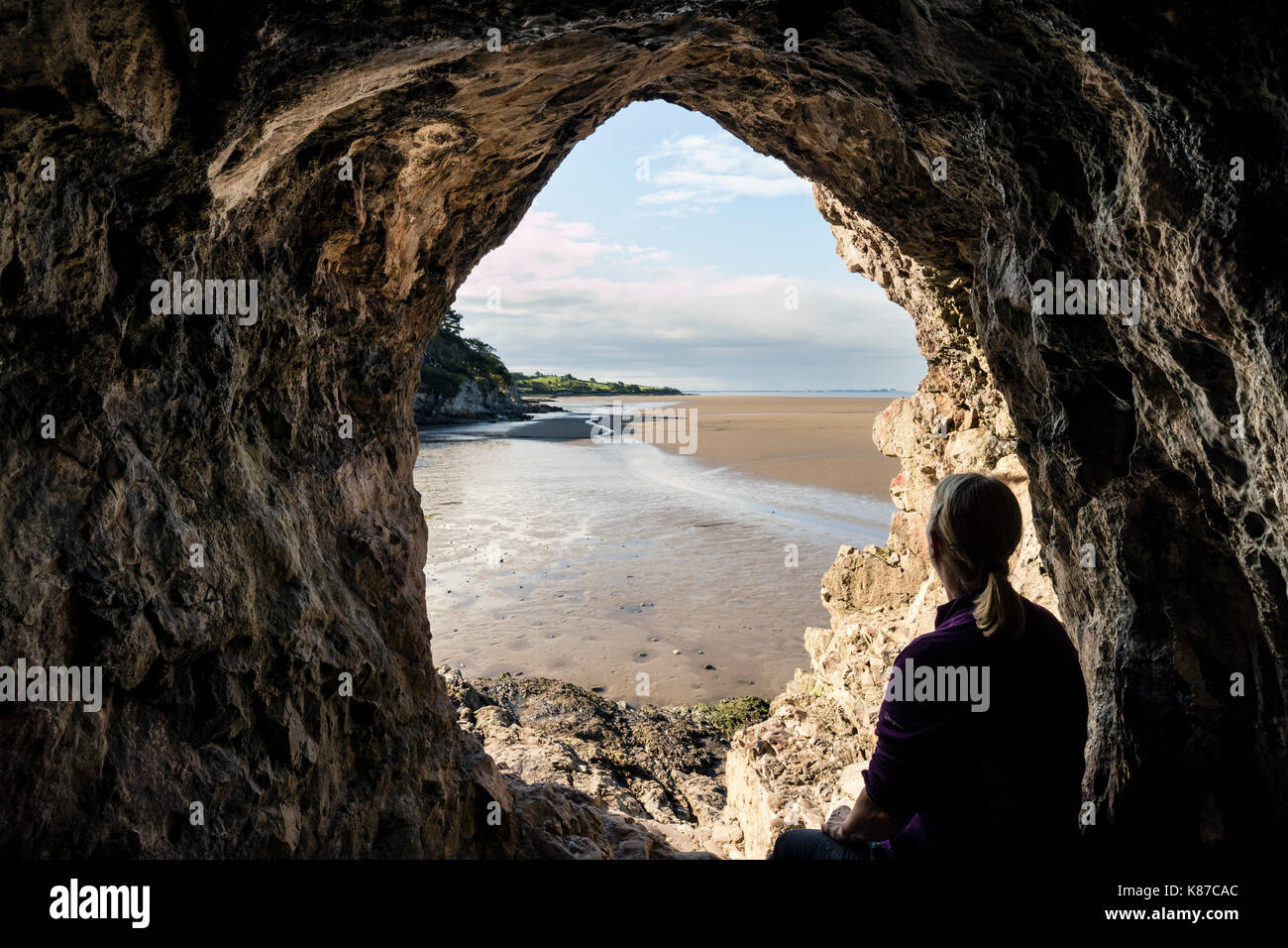 Walker Enjoying the View From the Inside of Cove Cave Across the Sands of Morecambe Bay, Silverdale, Lancashire, UK Stock Photo