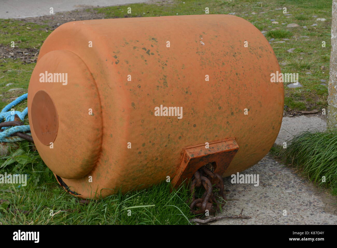 weathered buoyancy buoy float on dry land with chains and ropes with concrete and grassed area located at Nigg overlooking Cromarty Firth Scotland UK Stock Photo