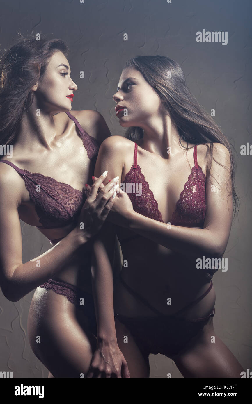 Two beautiful sexy lesbian in erotic underwear in embrace on a dark  background Stock Photo - Alamy