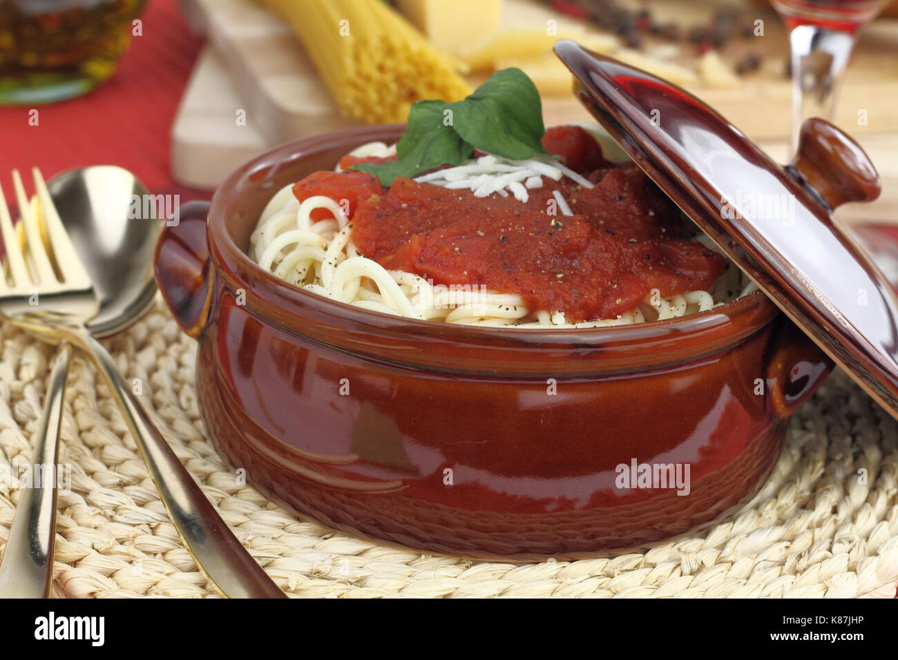 Spaghetti pasta with tomato sauce, cheese and basil in a clay pot Stock Photo