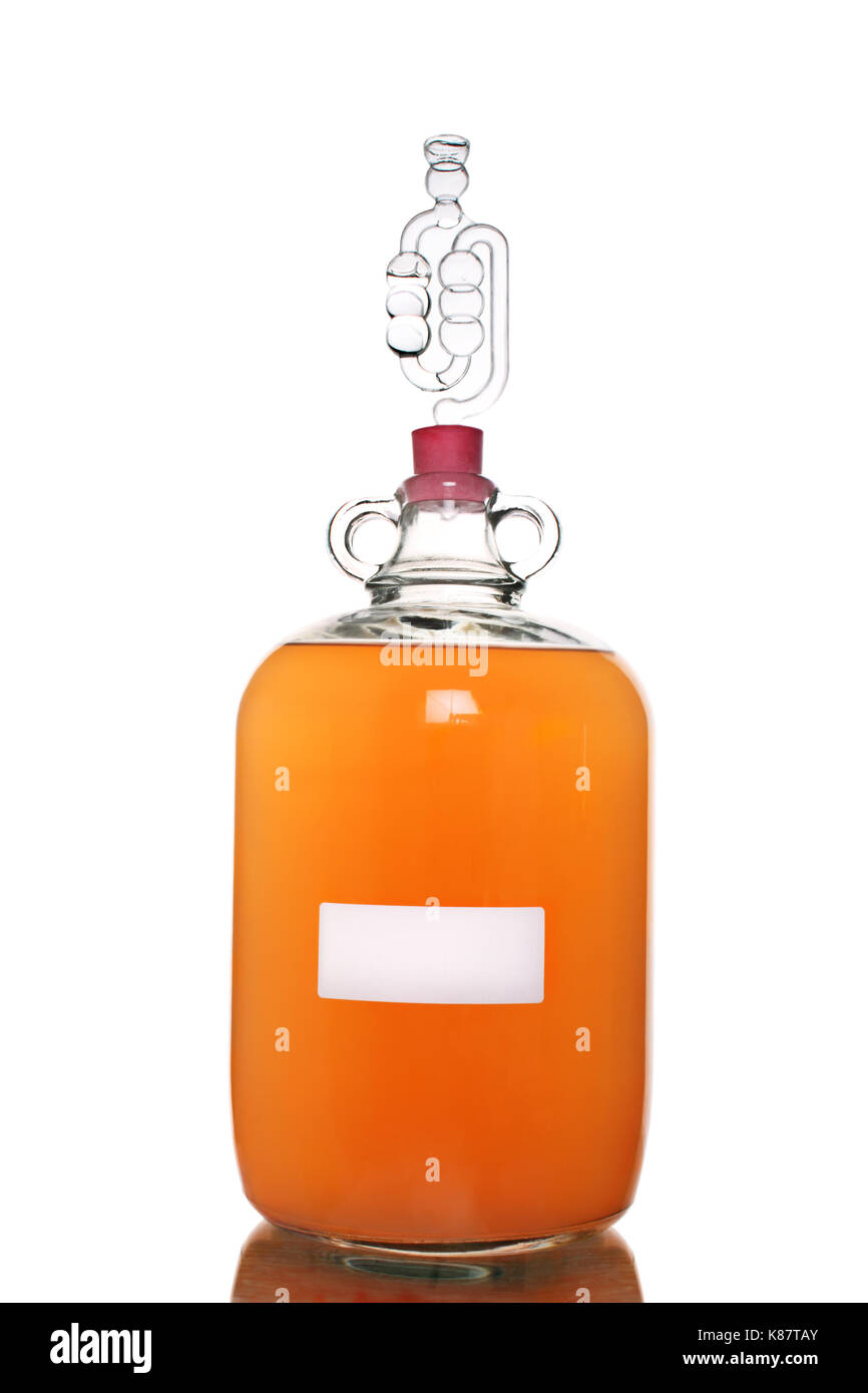 Peach wine fermenting in a demijohn, isolated on a white background. Stock Photo