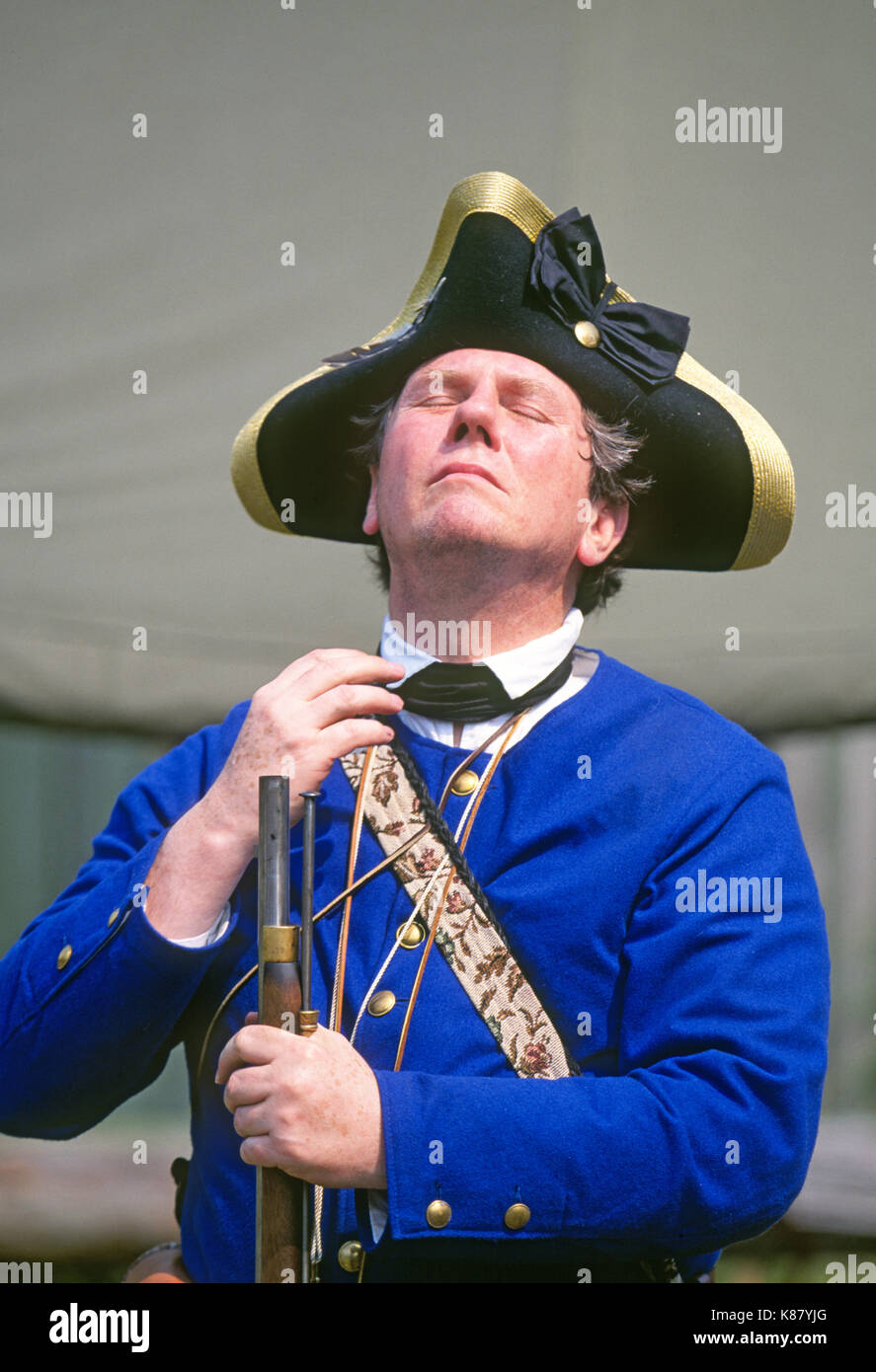 A man with a muzle loading rifle dressed in a Revolutionary War French Army uniform and wearing a tricorn hat. Stock Photo