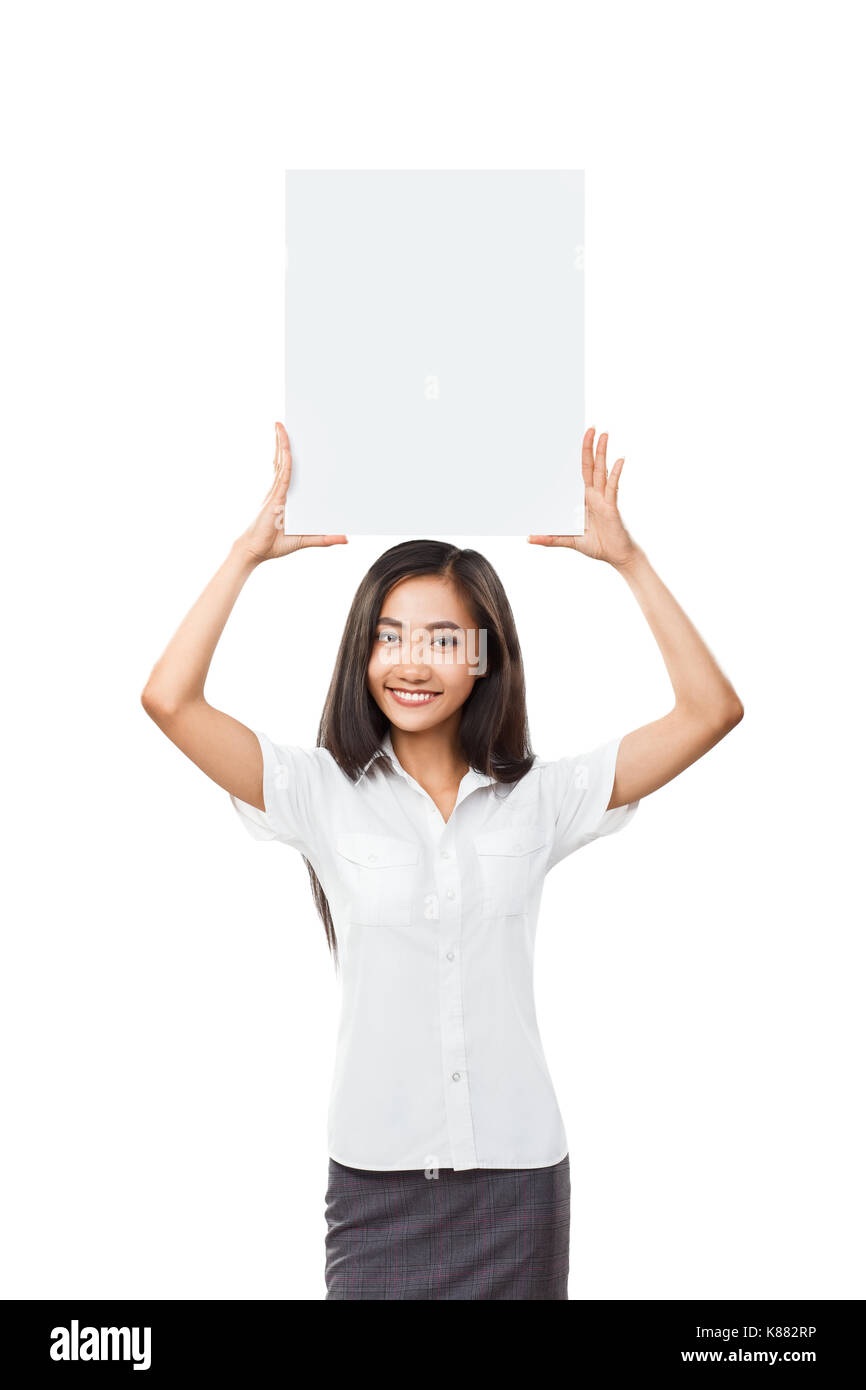 Asian business woman holding blank placard sign with copy space over her head. Half body isolated portrait of happy smiling female model with white si Stock Photo