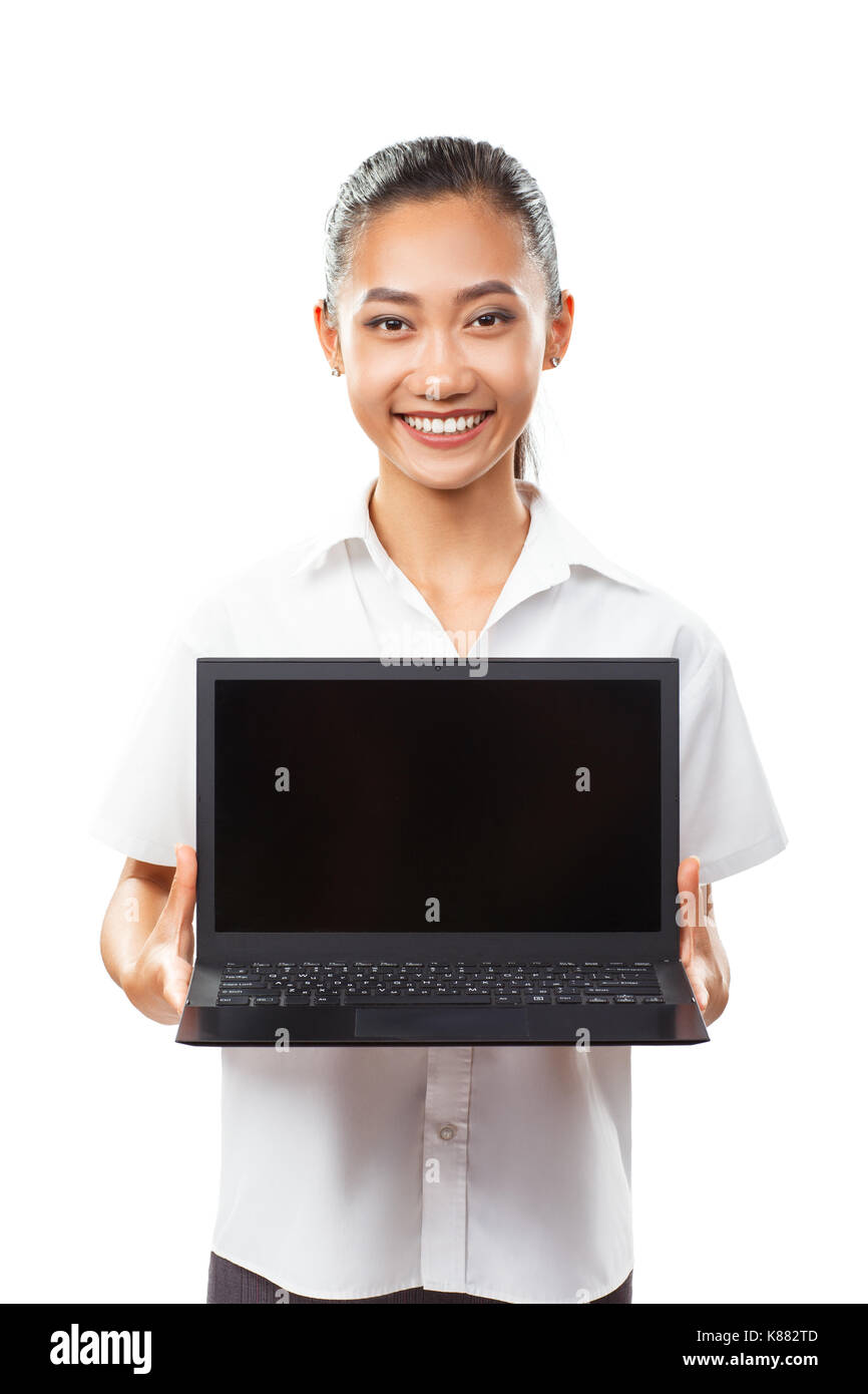 Portrait isolated of cute Asian young smiling woman holding and showing laptop. Black netbook with blank screen. Photo suitable for presentation compu Stock Photo