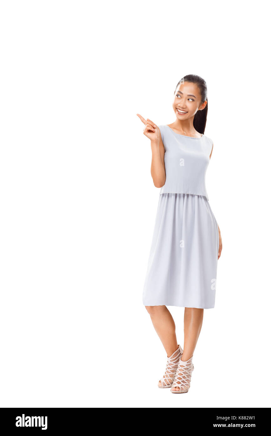 Full length portrait of happy Asian woman pointing finger. Happy female model in casual dress. Photo isolated on white background with copy space for  Stock Photo