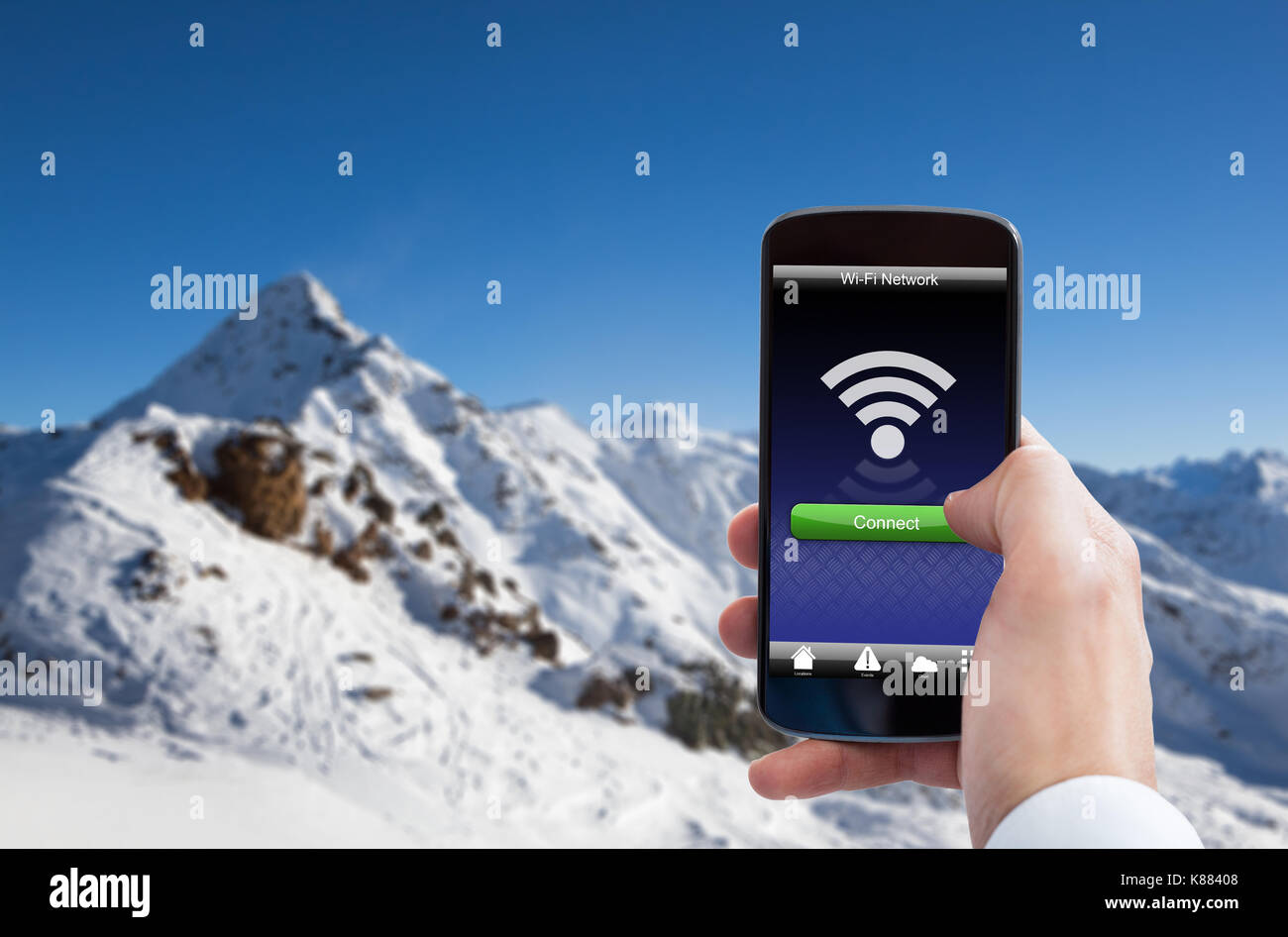 Close-up Of Hand Holding Mobile Phone With Wifi Signal In Snowy Mountain Stock Photo