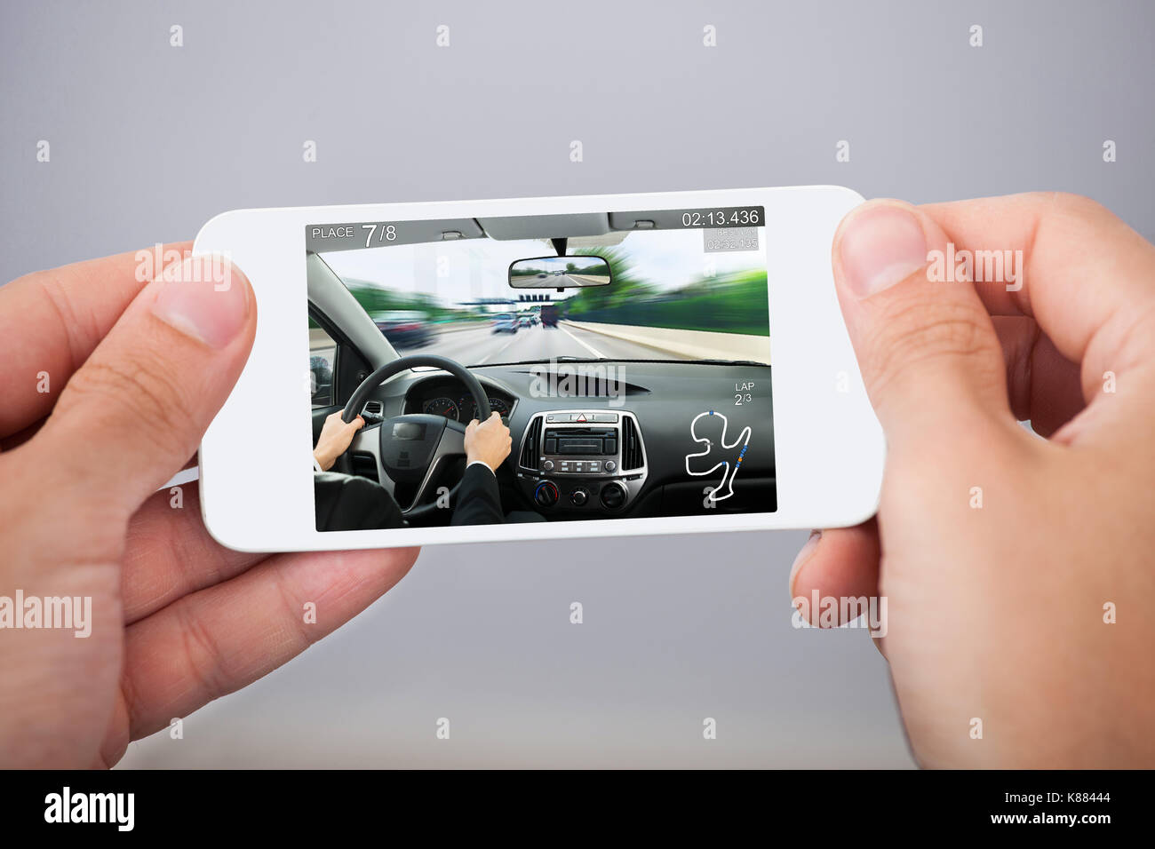 Close-up Of Person Hands With White Mobile Phone Playing Car Game Stock Photo