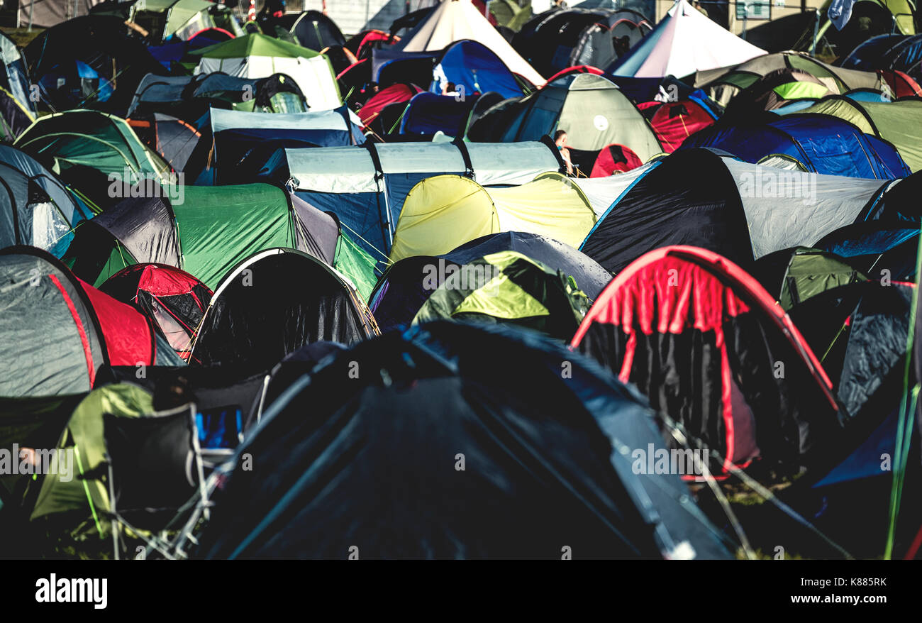 Tents on grass packed tightly together, pitched close together at an outdoor music festival in summer. A packed camping field. Stock Photo
