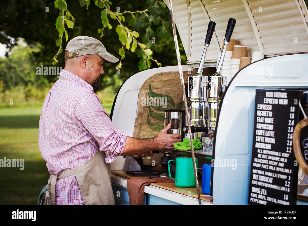 https://c8.alamy.com/comp/K886BX/bearded-man-wearing-apron-standing-by-blue-mobile-coffee-shop-making-K886BX.jpg