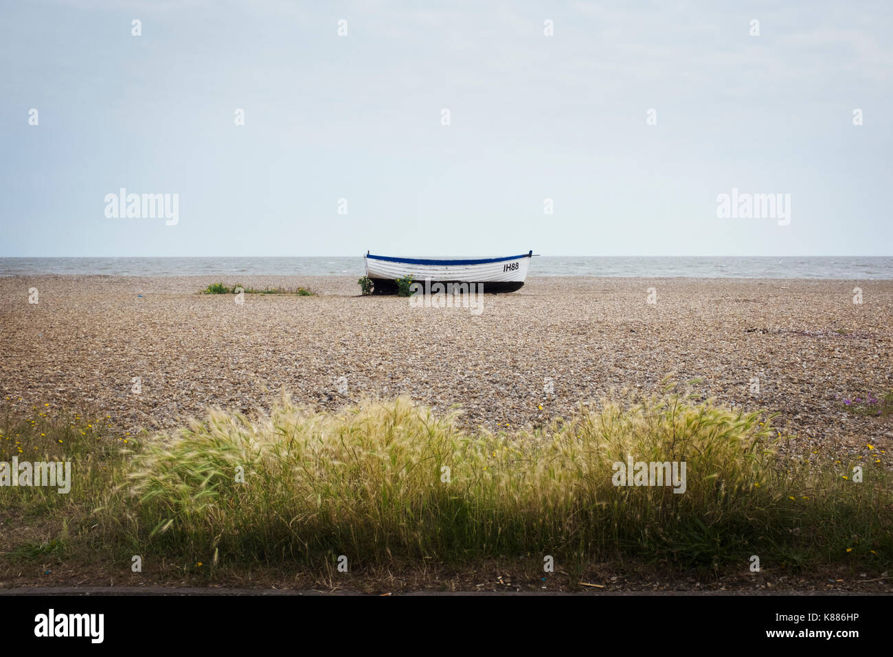 White fishing boat lying mid distance on pebble beach Stock Photo - Alamy