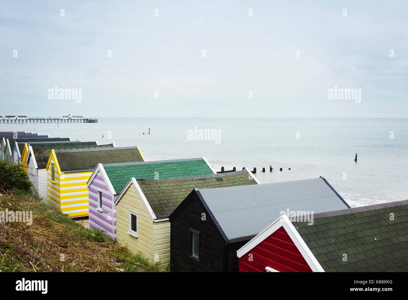 Row of colourful huts on a sandy beach under a cloudy sky. Stock Photo