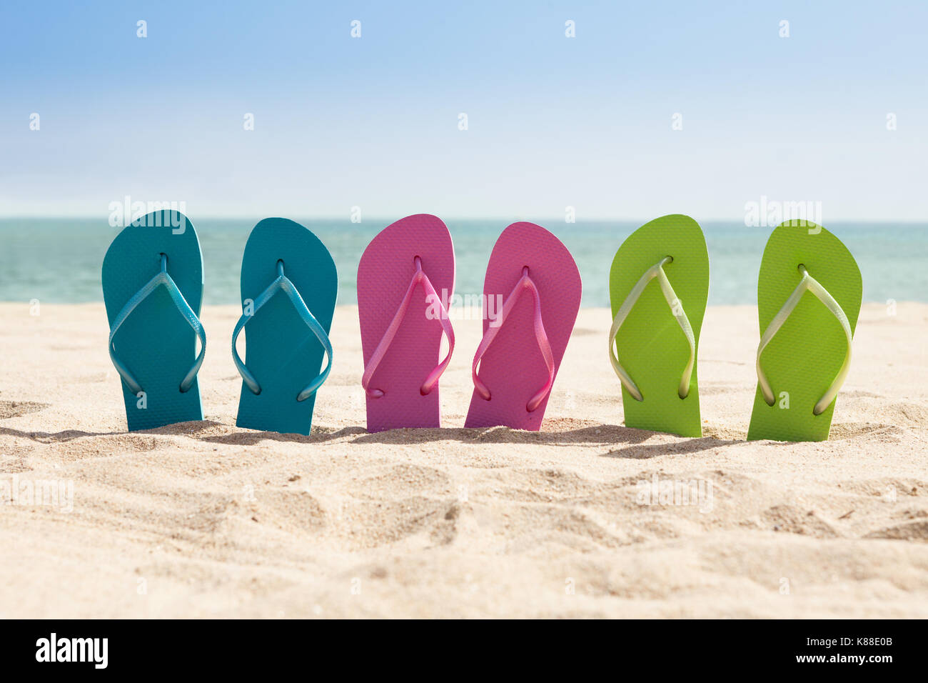 Colorful Three Pairs Of Flip-flops On Beach Stock Photo - Alamy