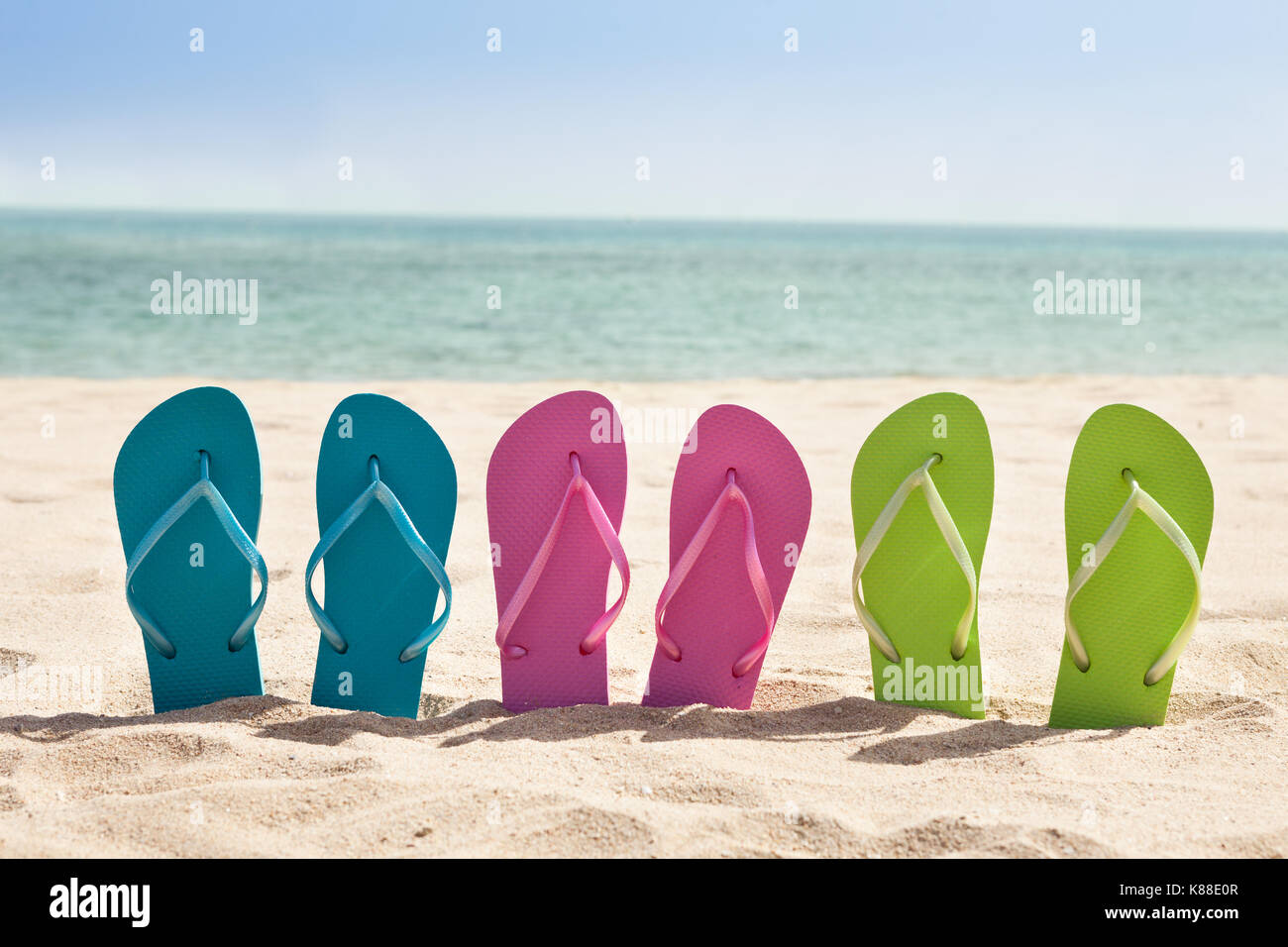 Colorful Three Pairs Of Flip-flops On Beach Stock Photo - Alamy