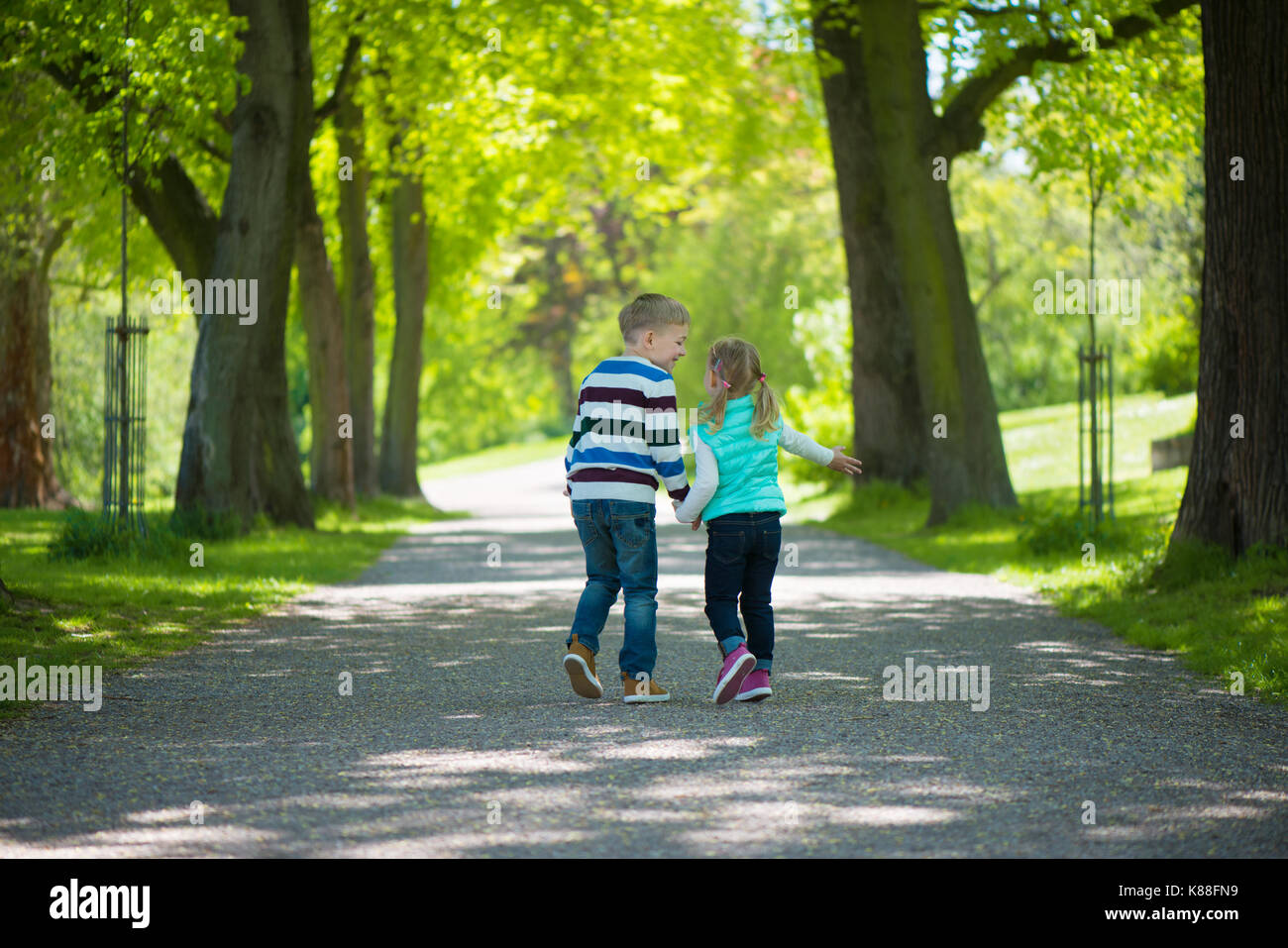 Two happy children walking in park. Holding hands Stock Photo