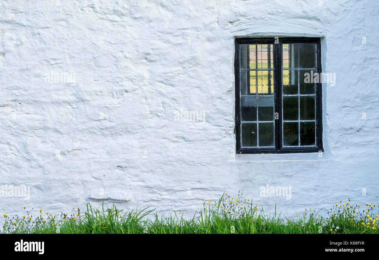 white, stone wall with a black window frame inset into the stone of an old Welsh Chapel Stock Photo