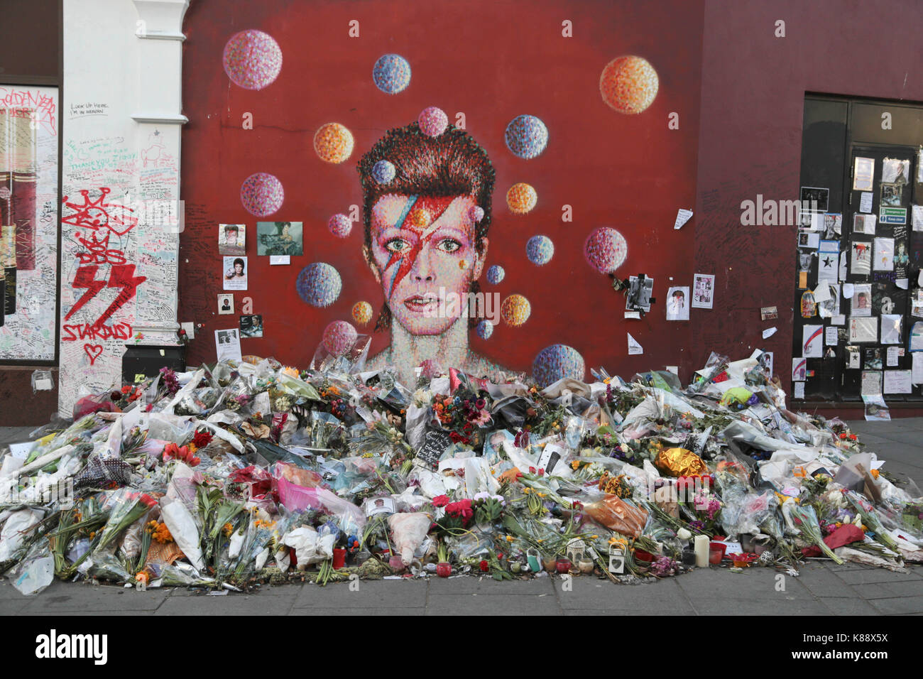 London UK 11th Feb 2016 Flowers are laid beneath a mural of David Bowie in Brixton. British music and fashion icon David Bowie died  at the age of 69  Stock Photo