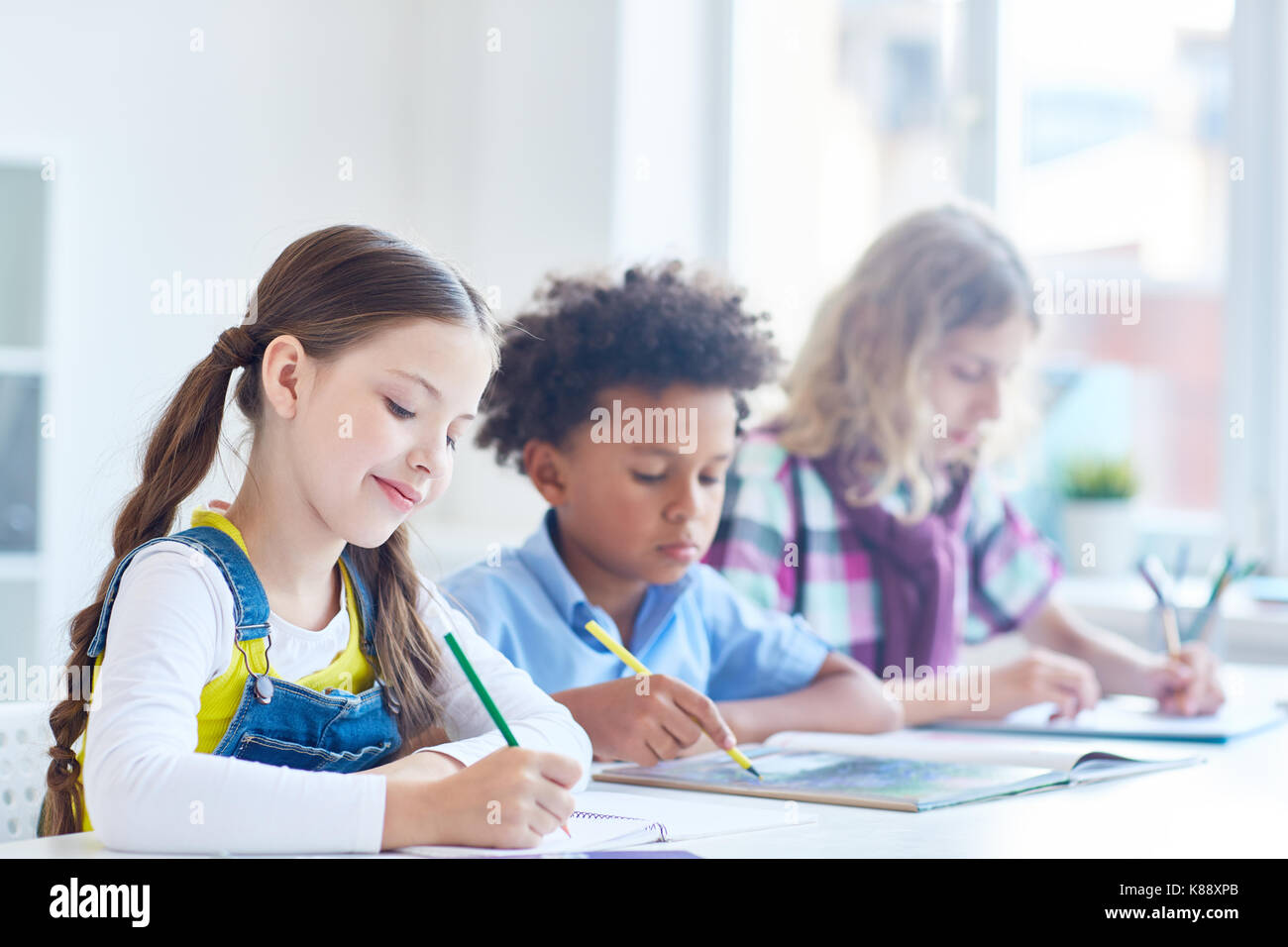 Group of clever schoolkids carrying out task or preparing for lesson Stock Photo