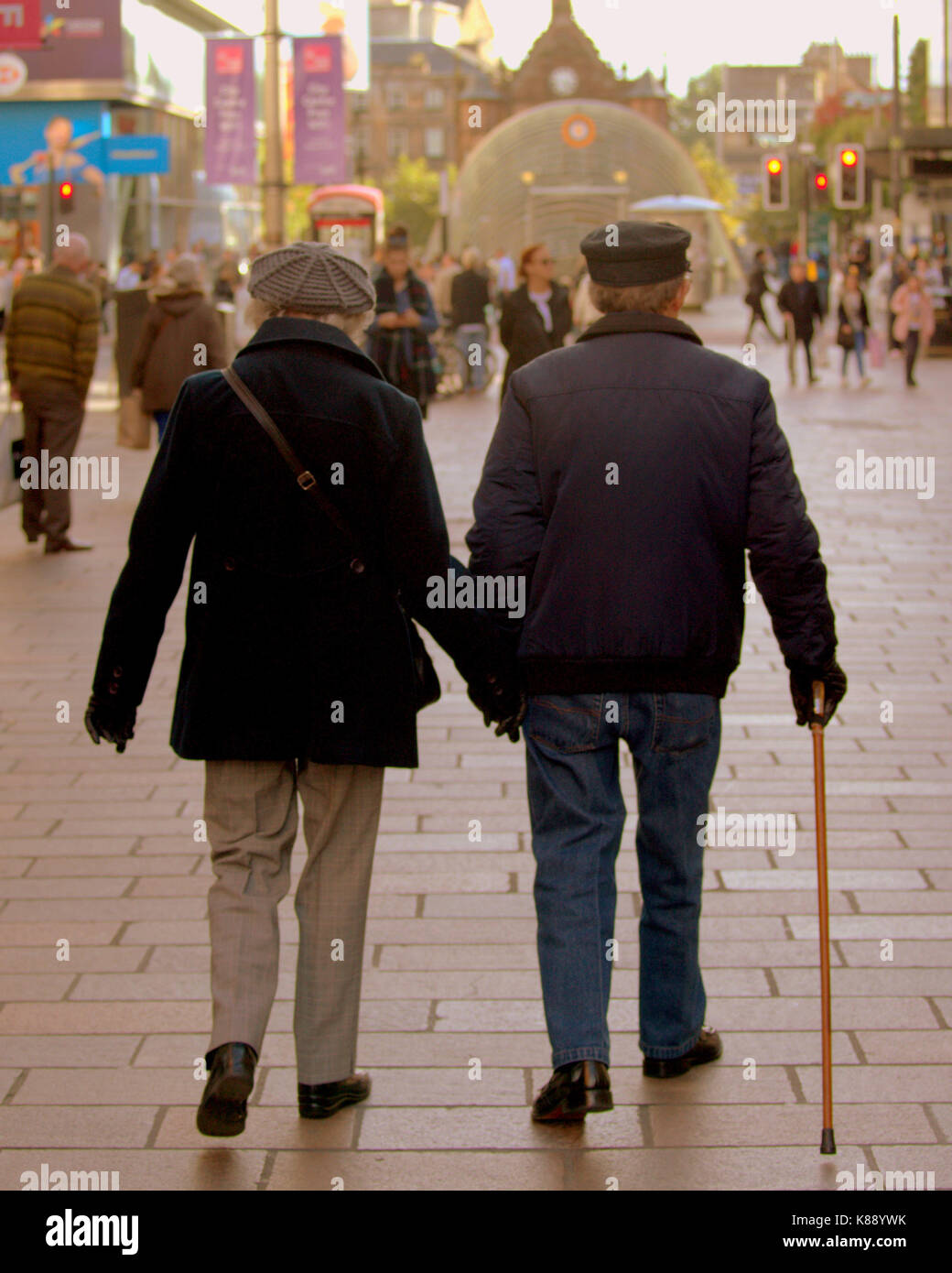 seniors old couple with walking stick holding hands  on Buchanan street the style mile Glasgow Stock Photo