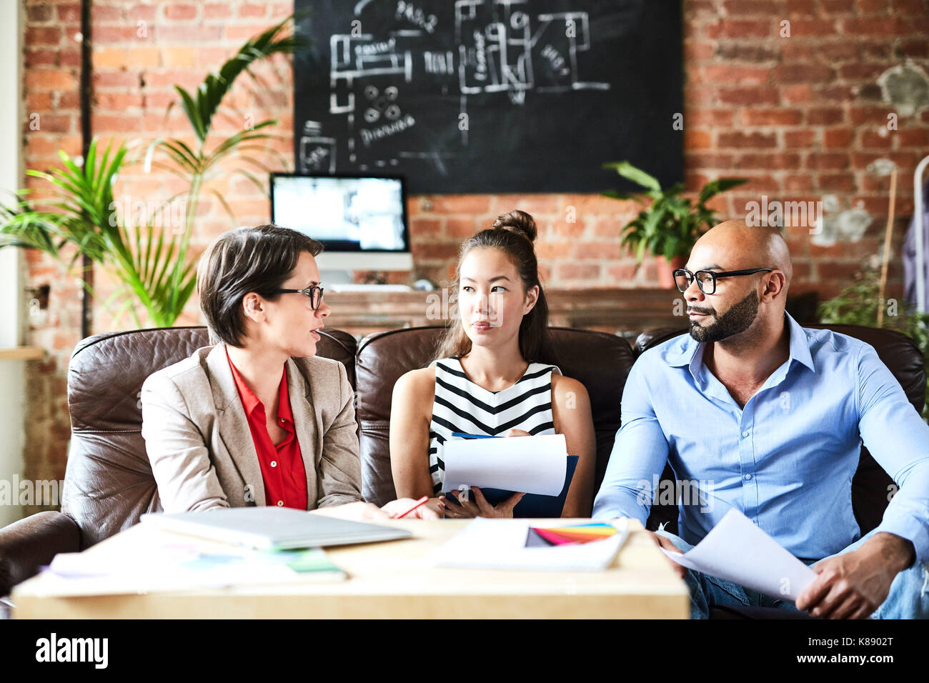 Three successful experts gathered for meeting to discuss new creative ideas Stock Photo