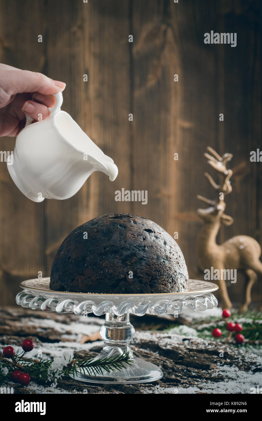 Christmas pudding and pouring cream with creative lighting Stock Photo