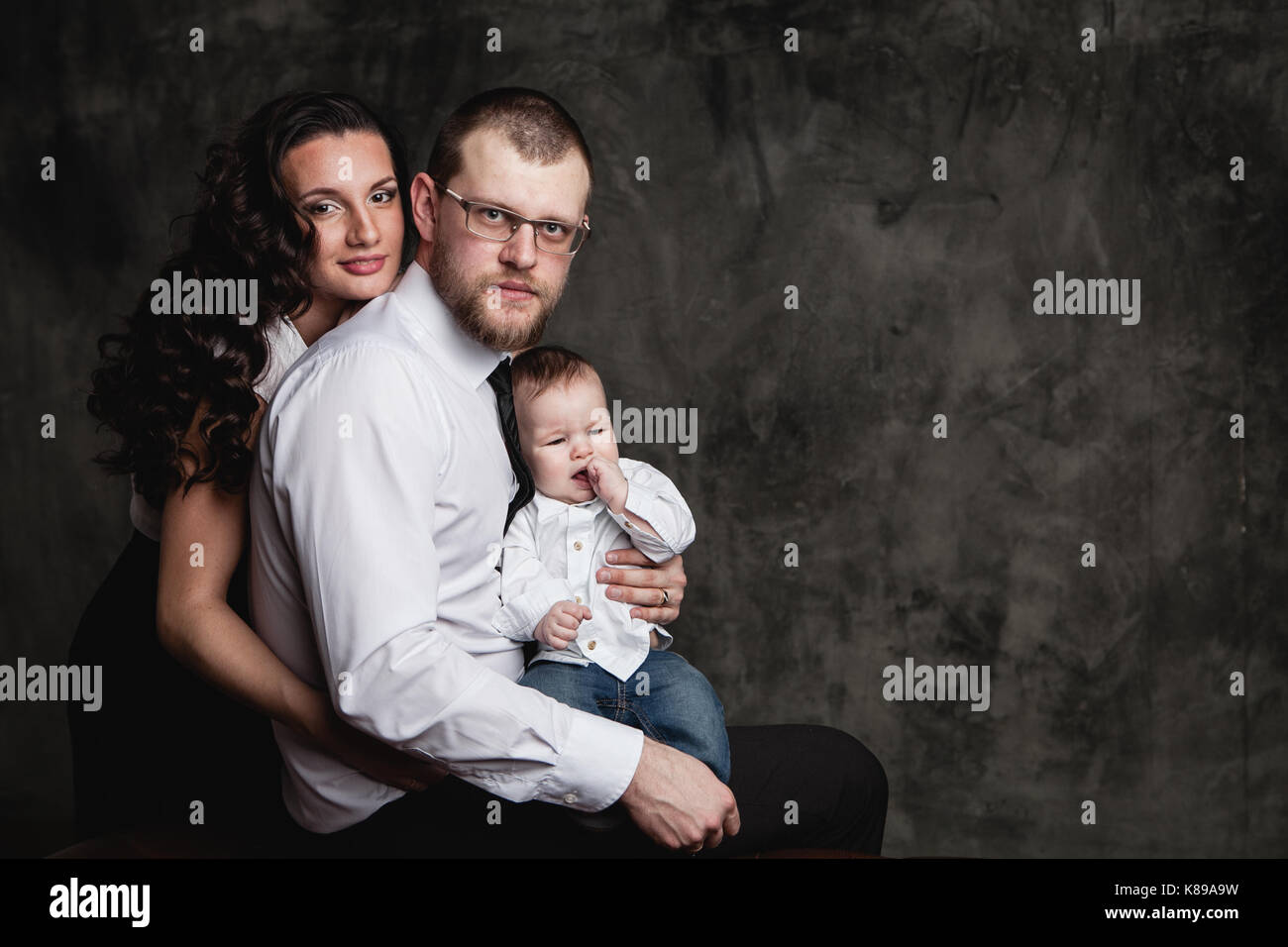 happy beautiful family with little kid sitting in studio Stock Photo