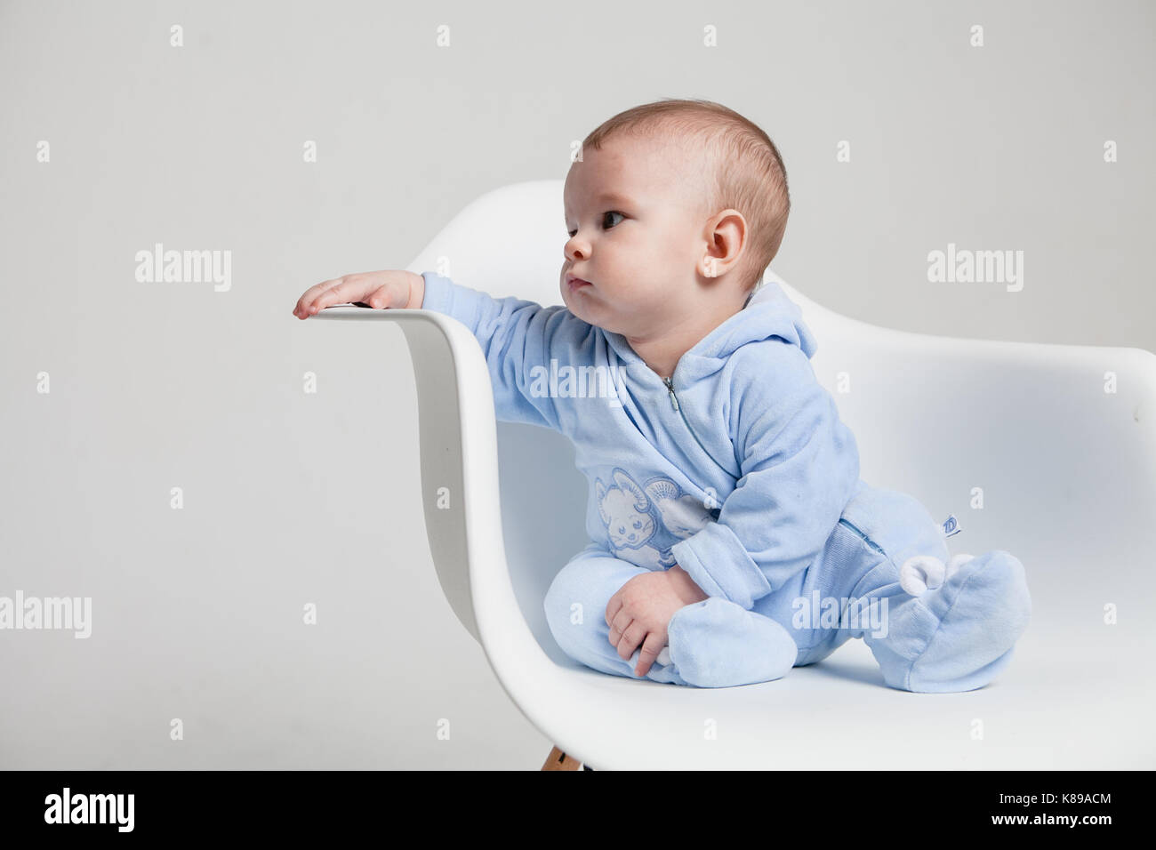 little boy one year old sitting on chair studio portrait white background Stock Photo