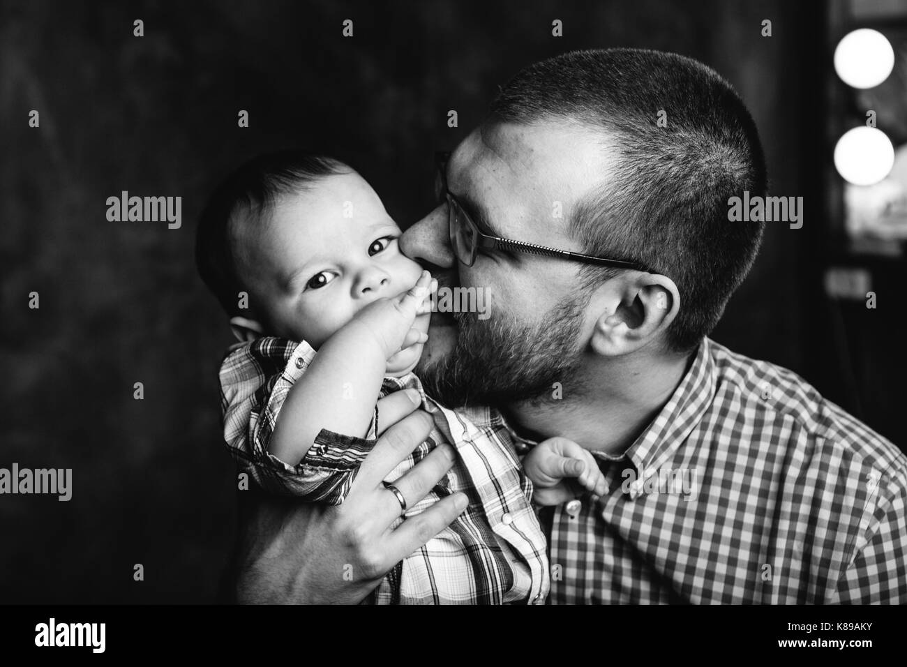 black and white portrait father kissing his little son Stock Photo