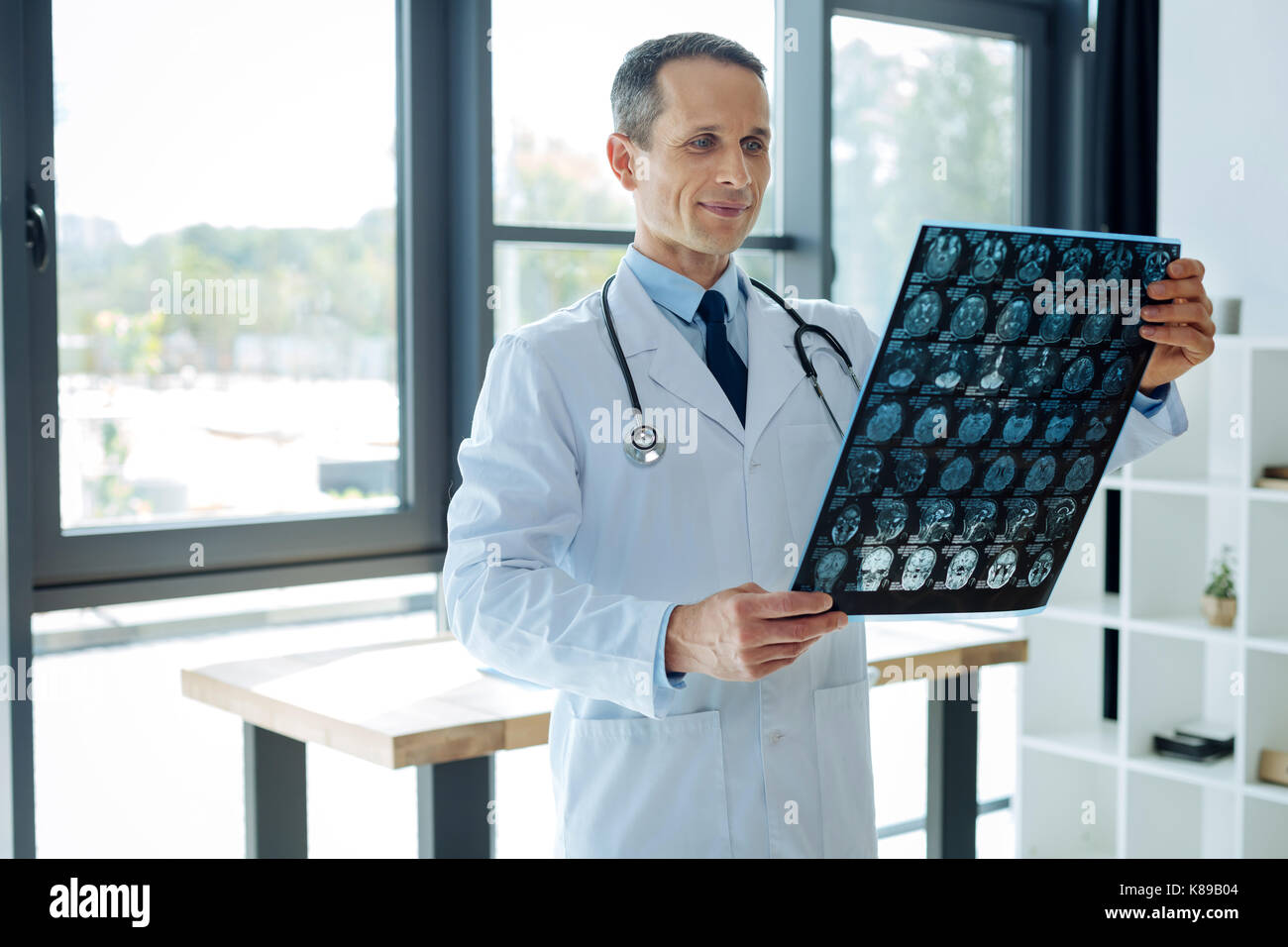 Delighted smart neurologist holding an X ray scan Stock Photo