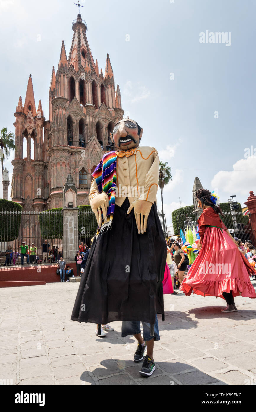 Giant papier mache puppets called mojigangas dance in front of the Parroquia de San Miguel Arcangel church during a children's parade celebrating Mexican Independence Day celebrations September 17, 2017 in San Miguel de Allende, Mexico. Stock Photo
