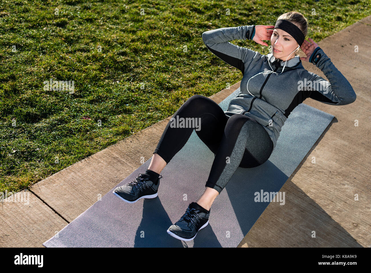 Young woman doing crunches for the abdominal muscles outdoors in Stock Photo
