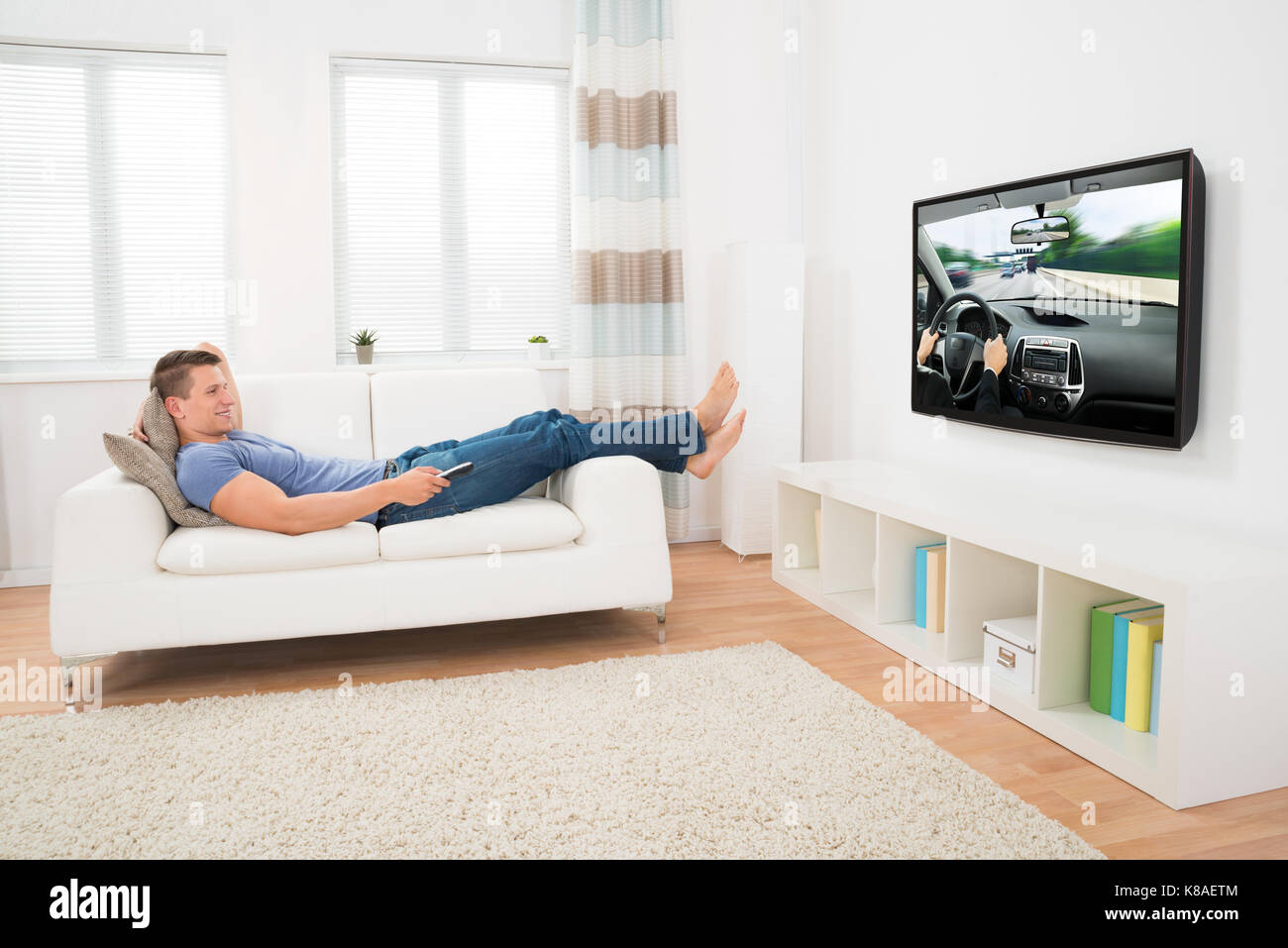 Happy Man Watching Movie While Lying On Sofa At Home Stock Photo