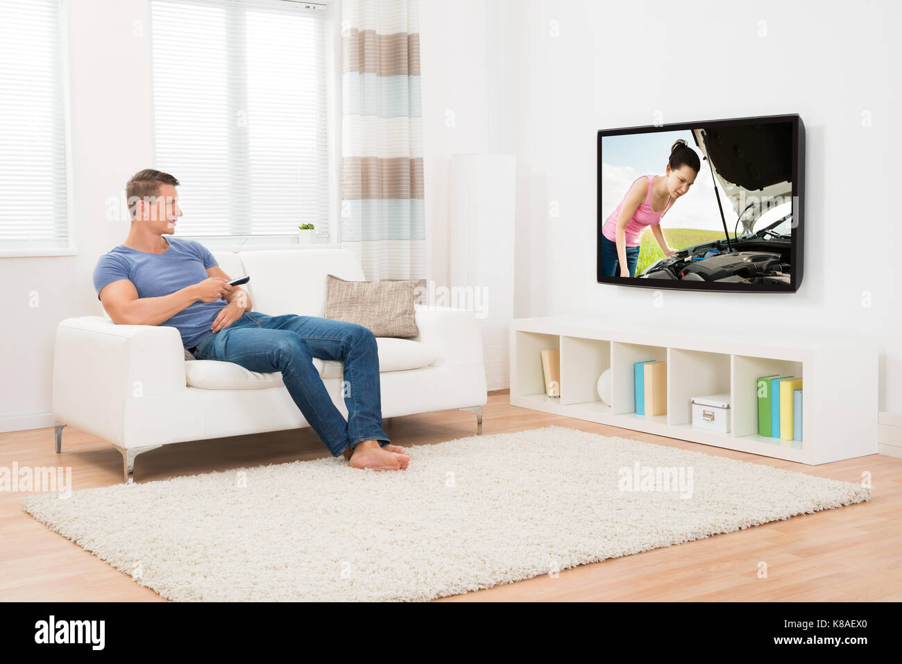 Young Man With Remote Control Watching Television In Living Room Stock Photo