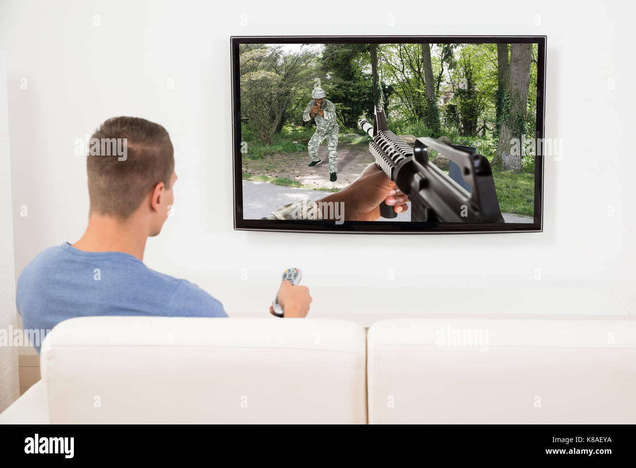 Young Man On Sofa Playing Game On Television Stock Photo