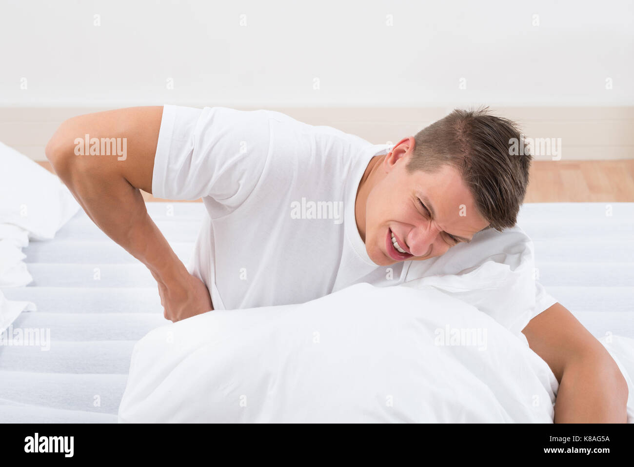 Young Man On Bed Suffering From Backache Stock Photo