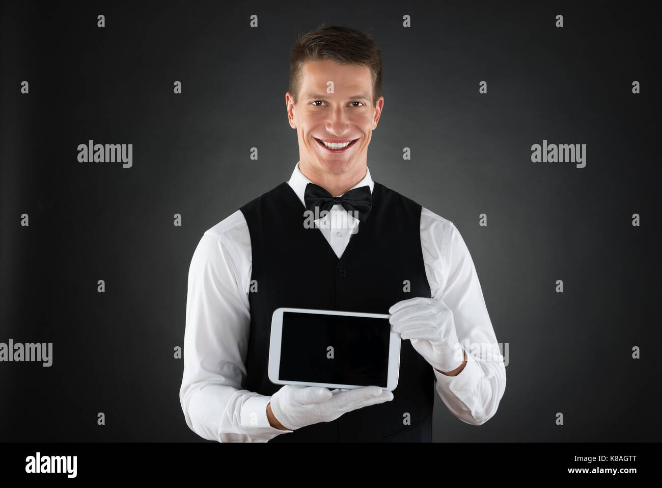 Portrait Of Young Happy Waiter Holding Cellphone Stock Photo